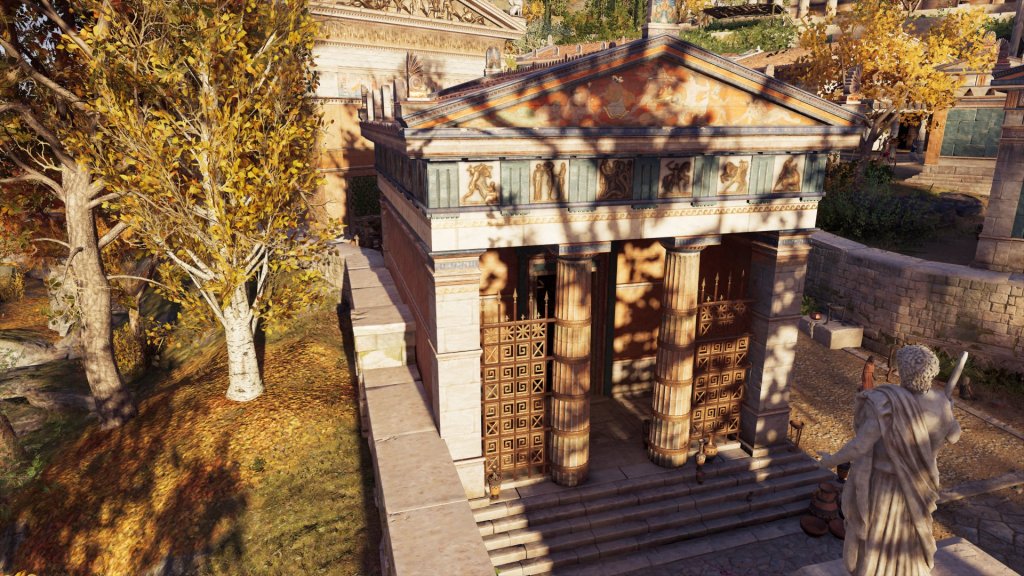 A small marble treasury with a two column porch and metopes from the Temple of Zeus at Olympia. There is a gold screen between the two columns and the outer wall. 